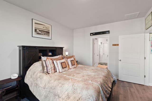 bedroom featuring dark wood-type flooring and ensuite bathroom