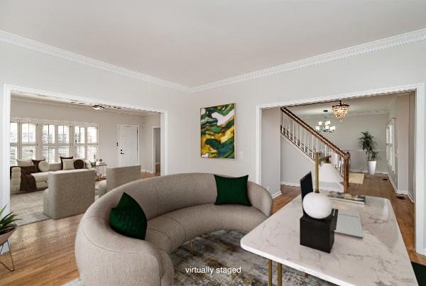 living room featuring wood-type flooring, ornamental molding, and a chandelier