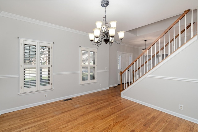 empty room with crown molding, wood-type flooring, and a chandelier