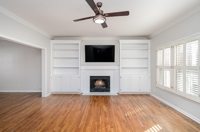 unfurnished living room featuring ornamental molding, a fireplace, and light hardwood / wood-style flooring