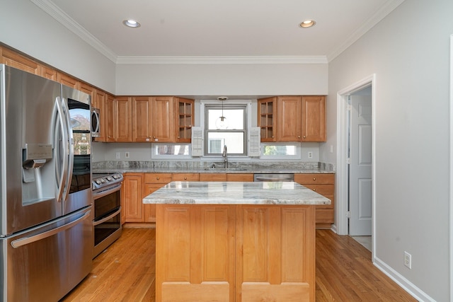 kitchen featuring stainless steel appliances, ornamental molding, a kitchen island, and light stone counters