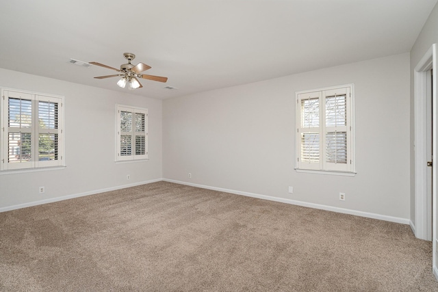 spare room with a wealth of natural light, ceiling fan, and carpet flooring