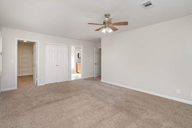 unfurnished bedroom with ceiling fan, ensuite bathroom, carpet flooring, and a closet