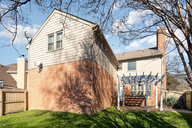 rear view of house featuring a pergola, a patio area, and a lawn