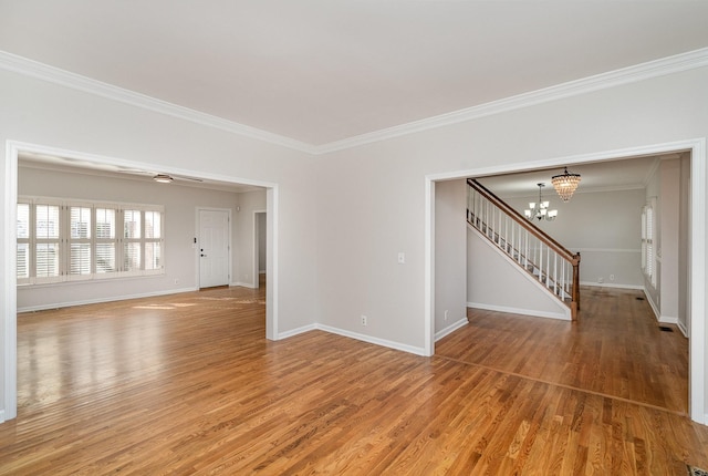 spare room featuring crown molding, wood-type flooring, and a chandelier