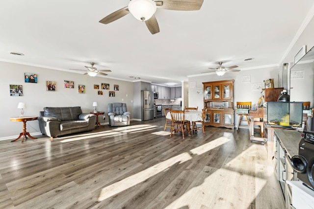 living room featuring ornamental molding, wood-type flooring, and ceiling fan