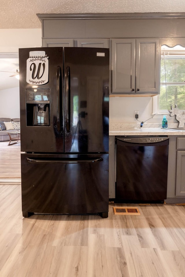 kitchen featuring gray cabinets, ceiling fan, black appliances, a textured ceiling, and light hardwood / wood-style flooring