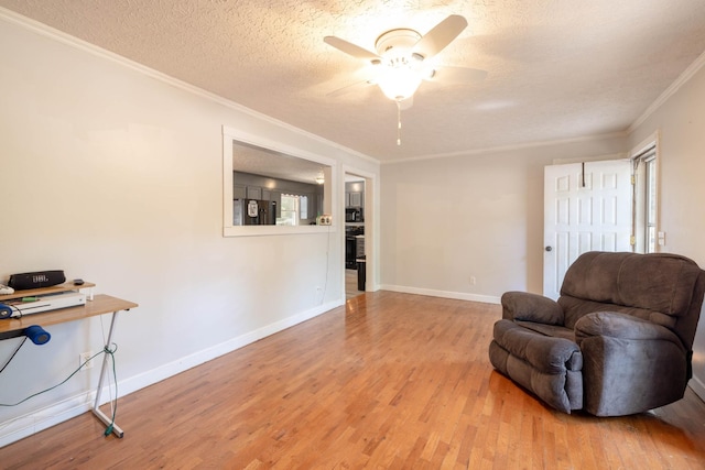 living area featuring crown molding, ceiling fan, a textured ceiling, and light wood-type flooring