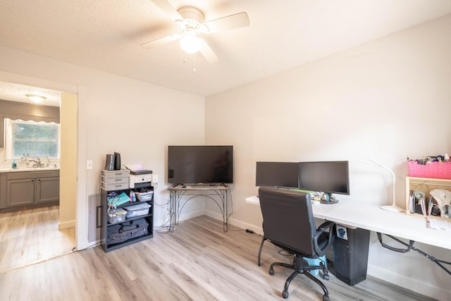 office space with ceiling fan, sink, light hardwood / wood-style flooring, and a textured ceiling