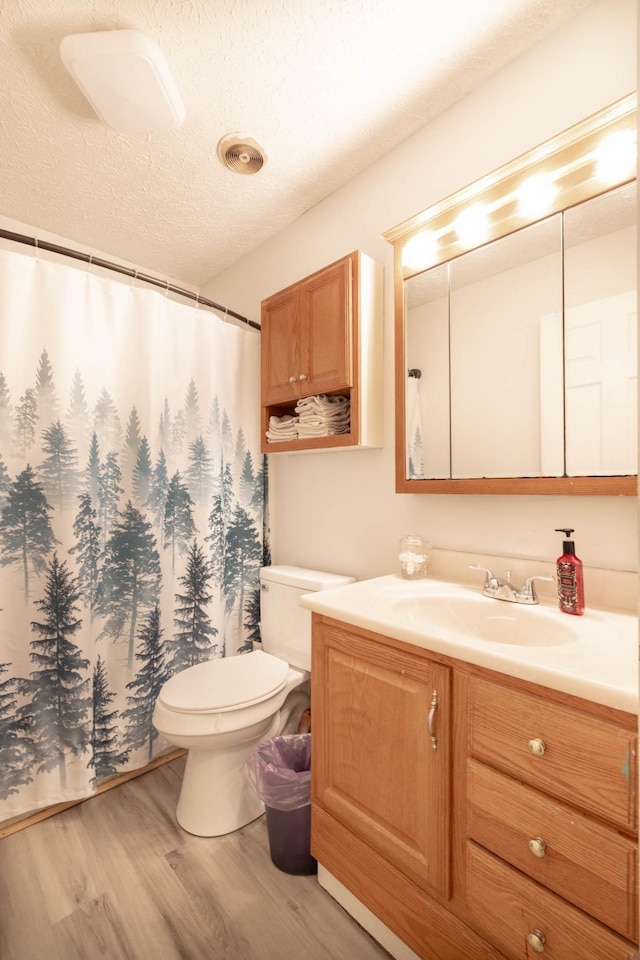 bathroom featuring vanity, toilet, hardwood / wood-style floors, and a textured ceiling