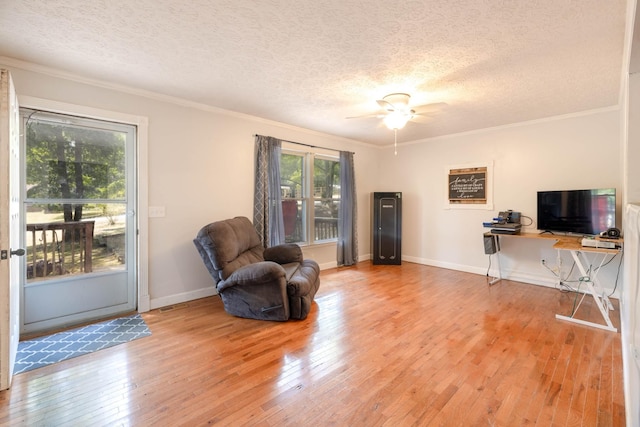 living area featuring crown molding, ceiling fan, wood-type flooring, and a textured ceiling