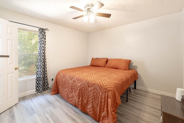 bedroom with multiple windows, ceiling fan, a textured ceiling, and light wood-type flooring