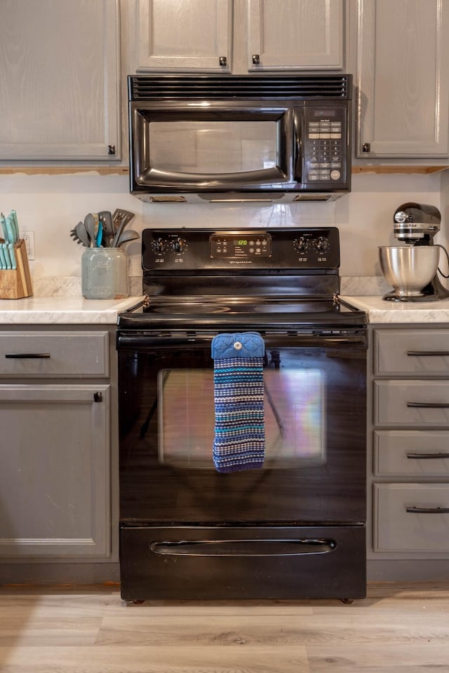 kitchen with gray cabinetry, light hardwood / wood-style floors, and black appliances