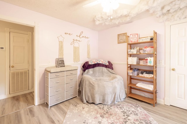 bedroom featuring ceiling fan, light hardwood / wood-style flooring, and a textured ceiling