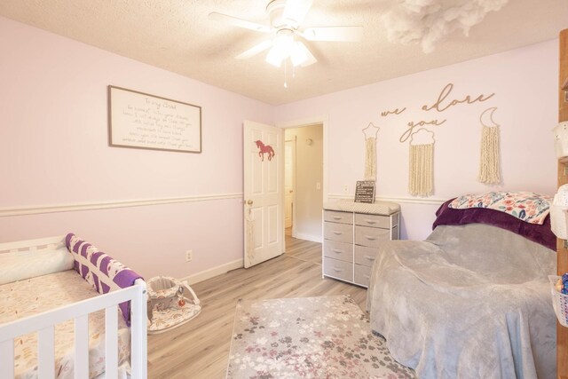 bedroom featuring ceiling fan, light hardwood / wood-style floors, and a textured ceiling