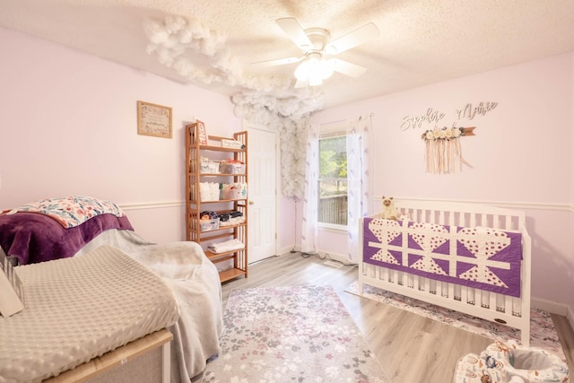 bedroom with ceiling fan, light hardwood / wood-style flooring, and a textured ceiling