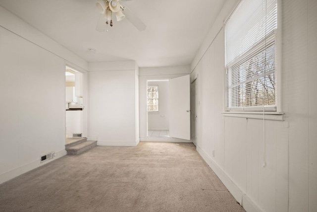 carpeted empty room featuring a healthy amount of sunlight and ceiling fan