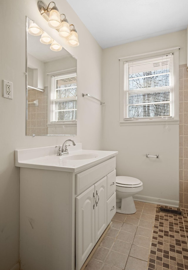 bathroom with tile patterned floors, vanity, toilet, and a wealth of natural light