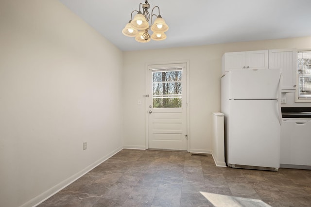 interior space with an inviting chandelier, white appliances, hanging light fixtures, and white cabinets