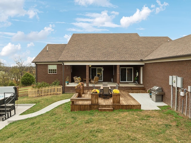 rear view of house with a wooden deck, a patio, and a lawn