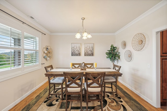 dining space featuring dark hardwood / wood-style flooring, crown molding, and a chandelier