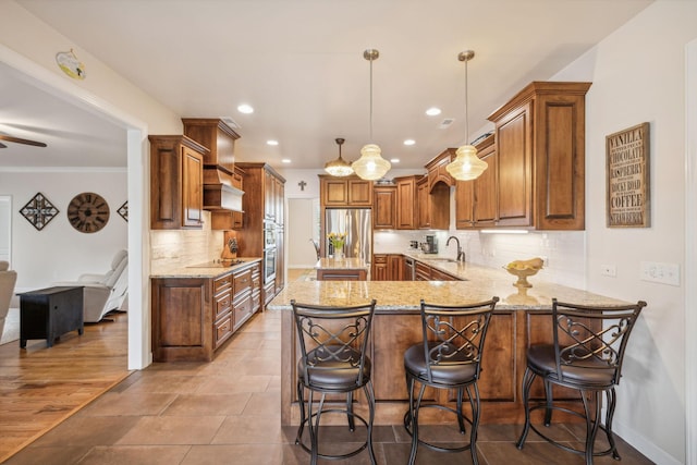 kitchen featuring sink, a breakfast bar, appliances with stainless steel finishes, decorative light fixtures, and kitchen peninsula