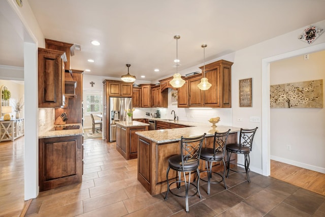 kitchen featuring sink, tasteful backsplash, hanging light fixtures, kitchen peninsula, and stainless steel appliances