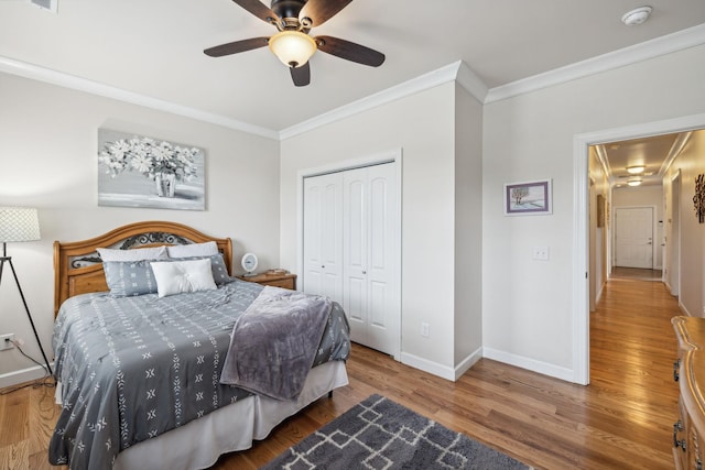 bedroom featuring crown molding, ceiling fan, wood-type flooring, and a closet