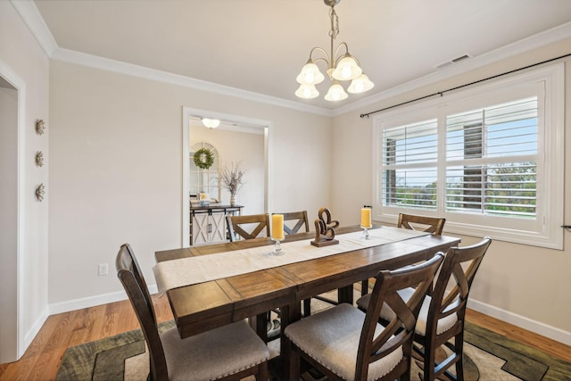 dining area with ornamental molding, hardwood / wood-style floors, and an inviting chandelier