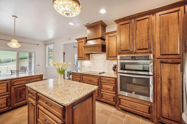 kitchen featuring tasteful backsplash, stainless steel double oven, decorative light fixtures, and a center island