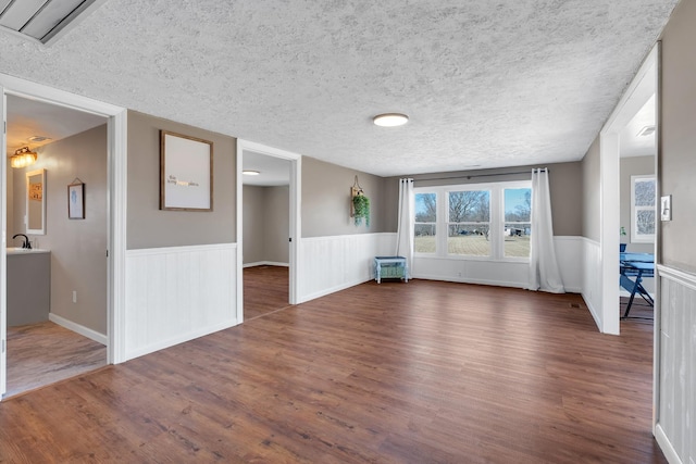 unfurnished living room featuring dark wood-type flooring and a textured ceiling