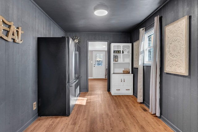 hallway with plenty of natural light, light hardwood / wood-style floors, and wood walls