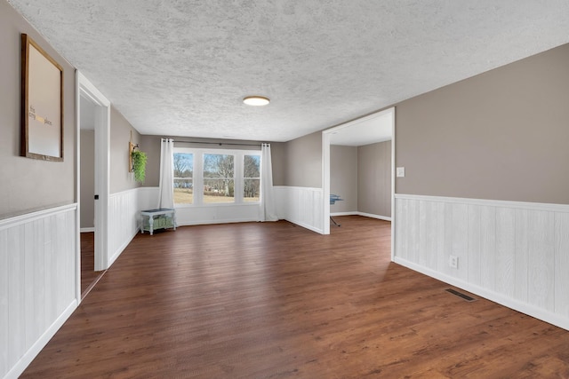 empty room with dark hardwood / wood-style flooring and a textured ceiling