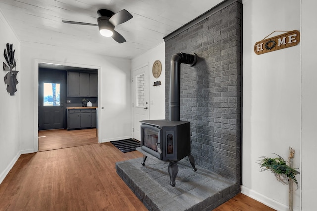 living room featuring hardwood / wood-style flooring, a wood stove, and ceiling fan