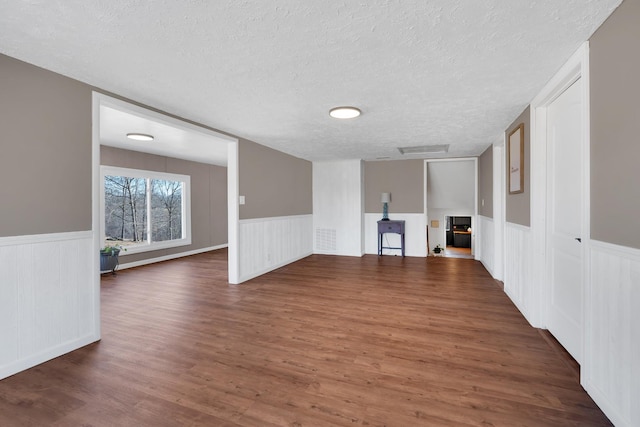 unfurnished living room featuring dark hardwood / wood-style flooring and a textured ceiling