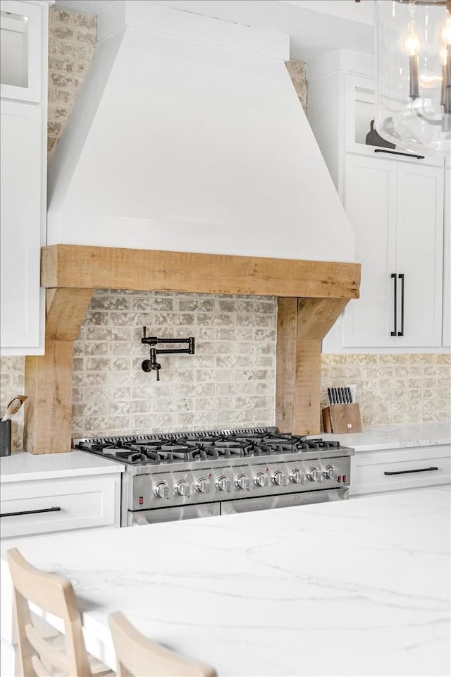 kitchen with white cabinetry, stainless steel range with gas cooktop, and tasteful backsplash