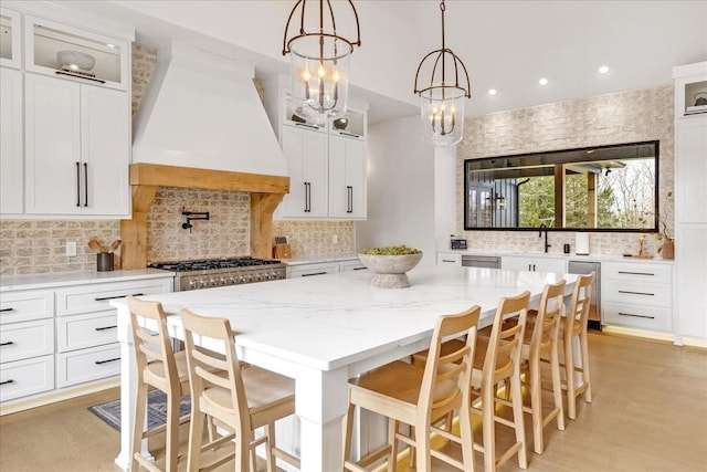 kitchen with premium range hood, white cabinetry, a kitchen breakfast bar, a center island, and light stone countertops