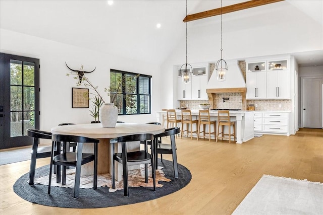 dining room featuring beamed ceiling, high vaulted ceiling, and light hardwood / wood-style floors