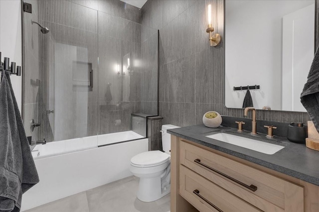 full bathroom with toilet, vanity, shower / bath combination with glass door, and tile walls