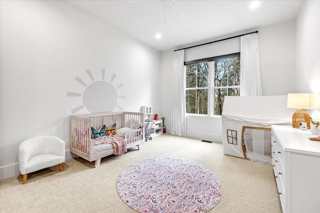 carpeted bedroom featuring a nursery area