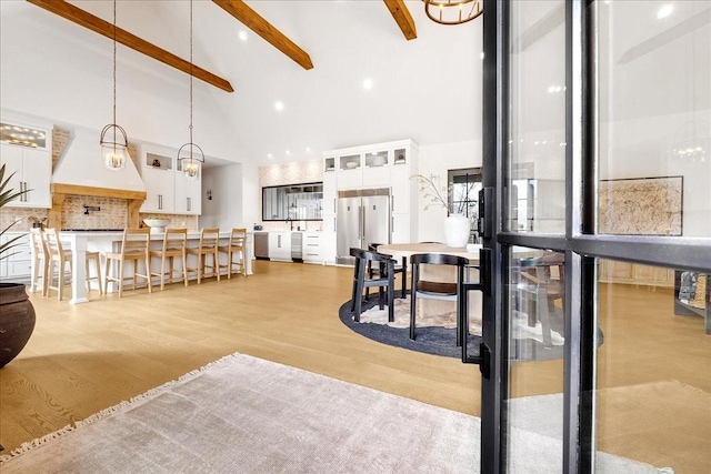 living room with beamed ceiling, high vaulted ceiling, and light wood-type flooring