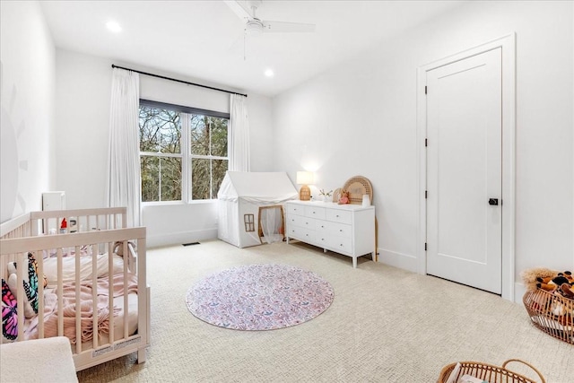 bedroom featuring a nursery area and light colored carpet