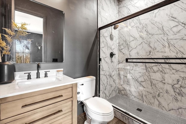 bathroom with a tile shower, vanity, and toilet