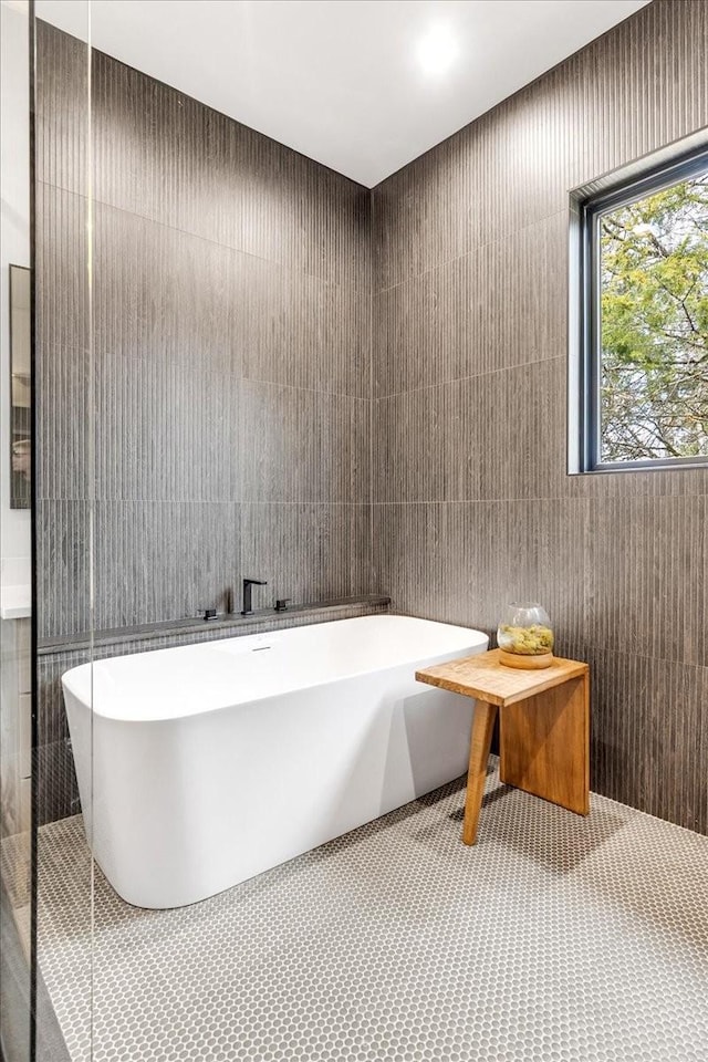 bathroom featuring a tub to relax in and tile walls