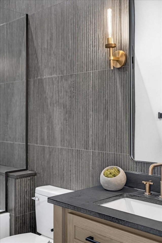 bathroom with vanity, tile walls, and toilet