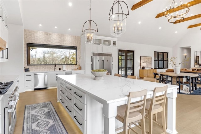 kitchen with white cabinetry, an inviting chandelier, hanging light fixtures, high quality appliances, and a kitchen island