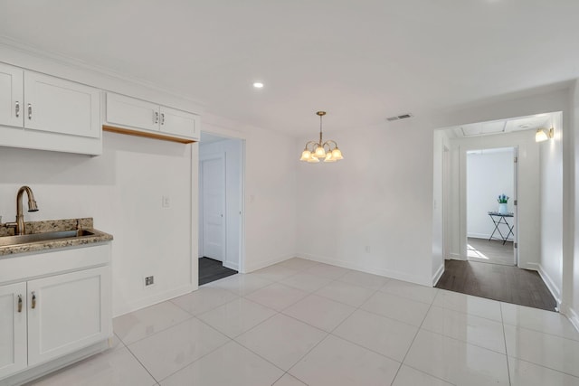 kitchen with pendant lighting, stone counters, sink, and white cabinets