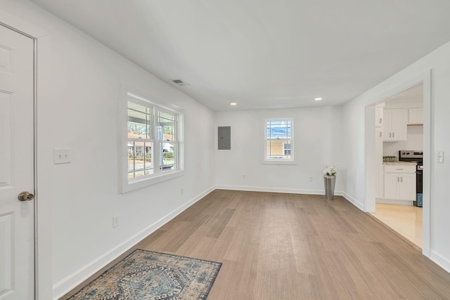 empty room featuring electric panel and light wood-type flooring