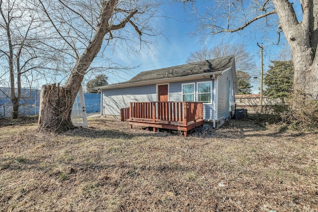 back of property with a wooden deck, a yard, and cooling unit