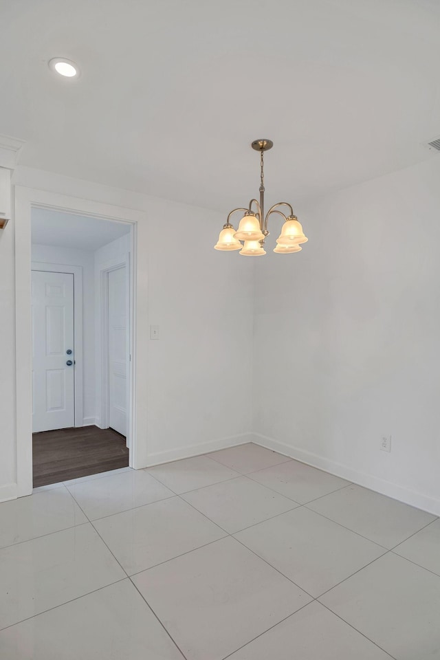 empty room with light tile patterned flooring and a notable chandelier